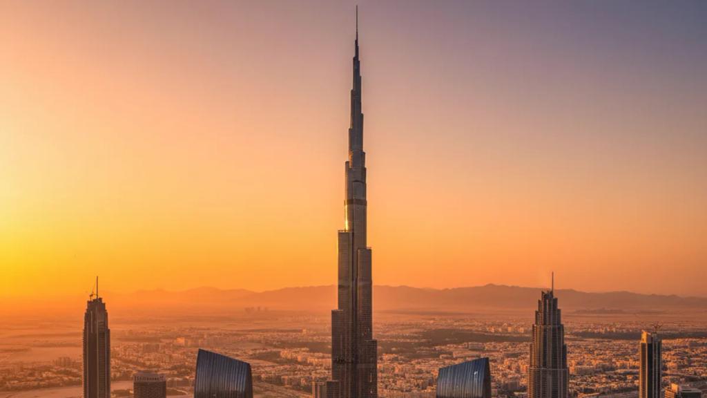 Alacakaranlıkta Dubai silüetinin önünde, telefonunda bağlı bir mobil sinyal gösteren gezgin