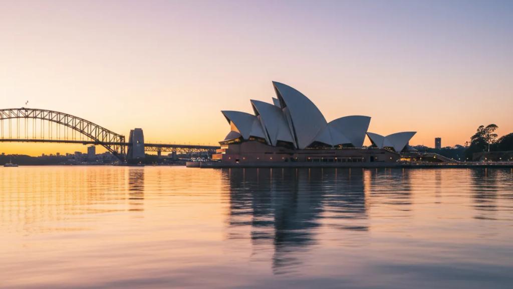Gün batımında Sydney Limanı'nda telefonunun çekip çekmediğini kontrol eden bir gezgin