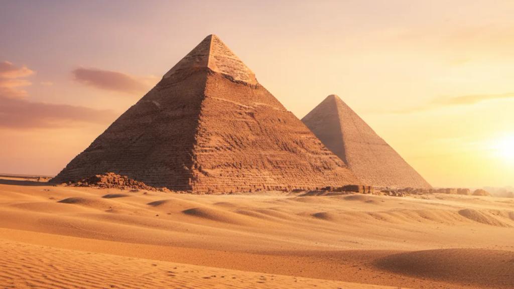 Gün batımında Giza piramitlerinin yakınında telefonunun çekip çekmediğini kontrol eden gezgin