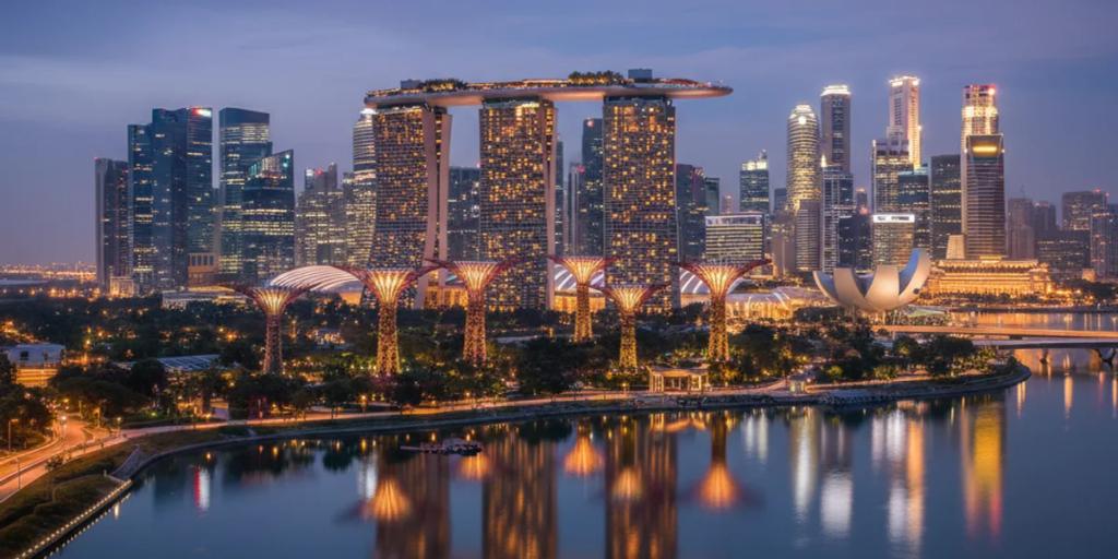 Mavi saatte parıldayan Marina Bay silüeti ve Gardens by the Bay'in Süperağaçları