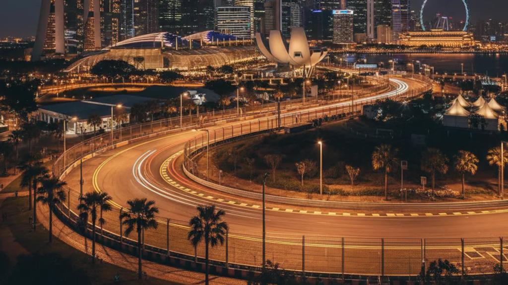 Marina Bay sokak pistinde projektörler altında yarışan Formula 1 araçları ve arkada Singapur silüeti