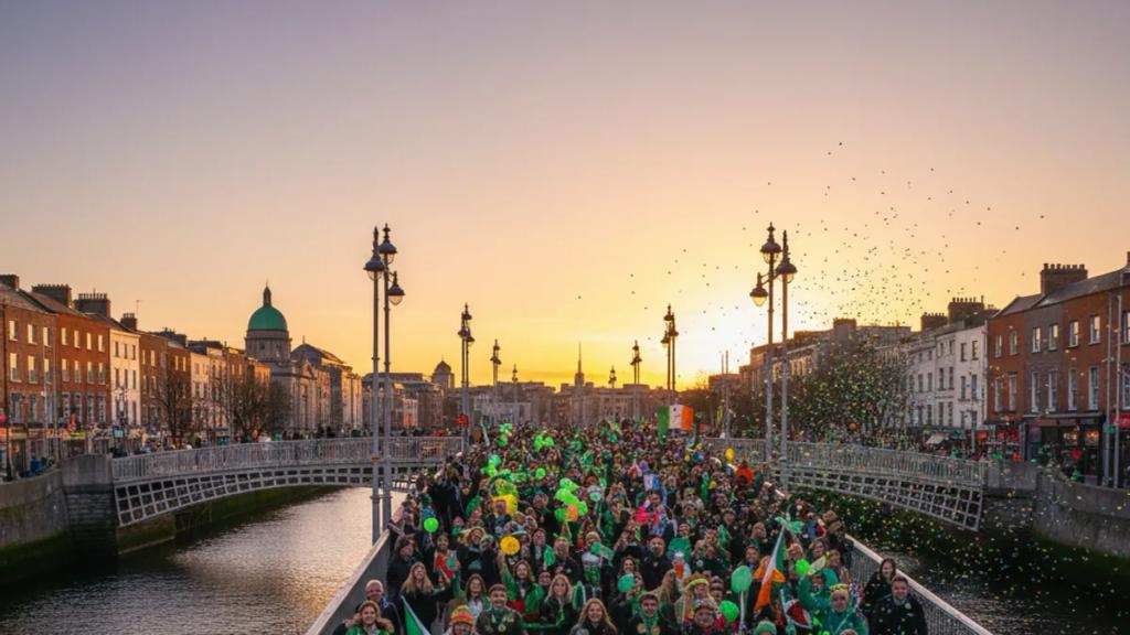 Dublin'de O'Connell Street'i dolduran yeşiller içindeki kalabalık ve GPO'nun önünden geçen St Patrick's Festivali geçit platformu